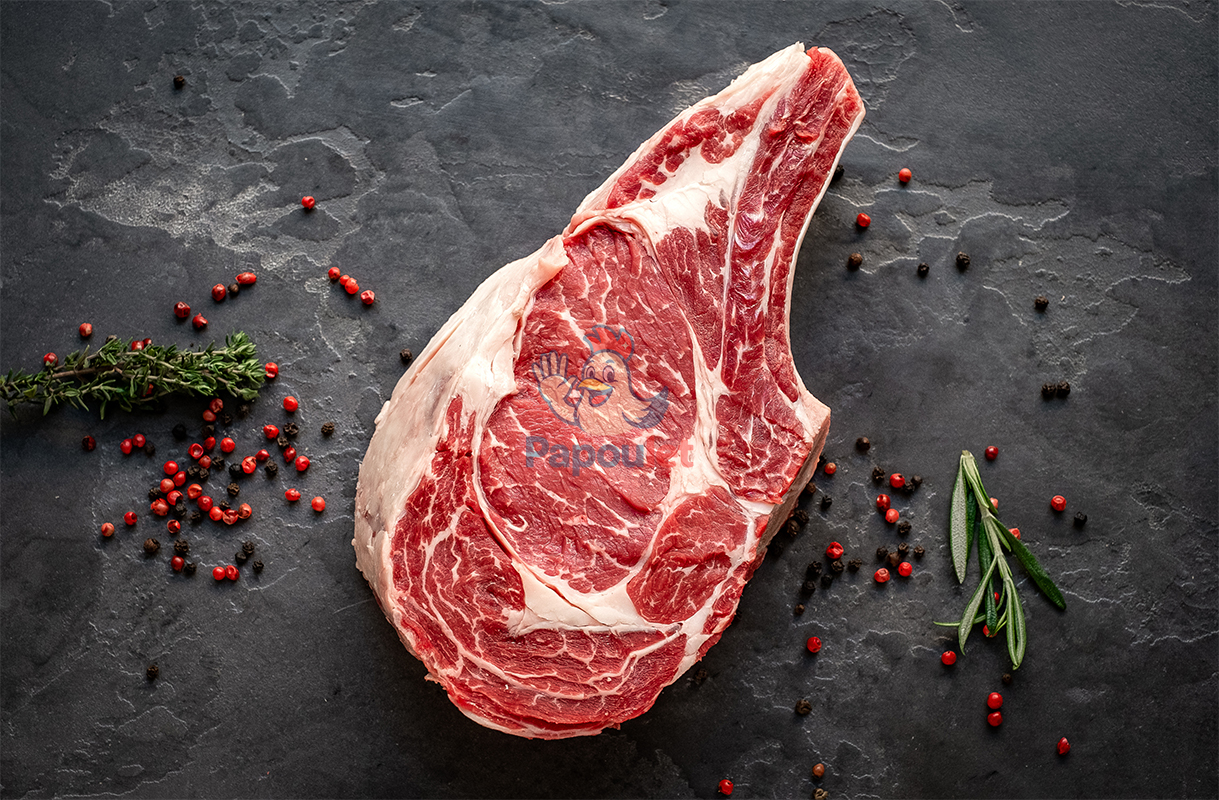 raw cowboy steak with seasonings on stone background, prime rib